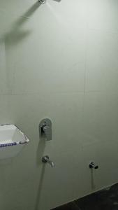 a bathroom stall with a white wall with a faucet at Munot residency in Manmād +12 photos