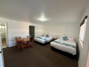 a hotel room with two beds and a table at Riviera Motel Bundaberg in Bundaberg +44 photos