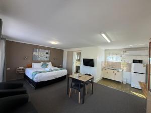 a hotel room with a bed and a table at Riviera Motel Bundaberg in Bundaberg
