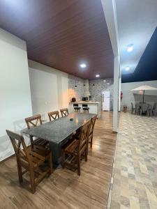 a dining room with a table and chairs and a kitchen at Pousada Diamante in Piranguçu