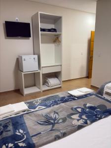 a room with a bed with a television and a rug at Pousada Diamante in Piranguçu +8 photos