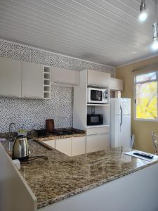 a kitchen with white cabinets and a white refrigerator at Condomínio Central Meu Cantinho in Uruguaiana
