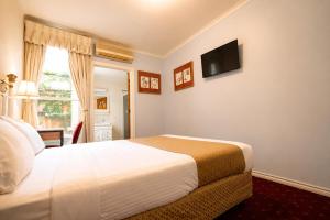 a bedroom with a bed and a television on the wall at Georgian Court Inn in Melbourne