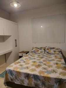 a bedroom with a bed with a colorful comforter at Condomínio Central Meu Cantinho in Uruguaiana +2 photos