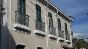 a building with green shuttered windows on a street at Cachoeira Apart Hotel in Cachoeira