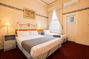 a hotel room with two beds and a window at Georgian Court Inn in Melbourne