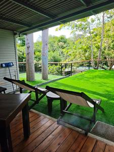 a table and chairs on a porch with a green lawn at Monkey House Hostel & Guest House Koh Samui in Chaweng Noi Beach +29 photos