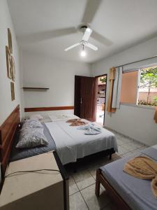 a bedroom with two beds and a ceiling fan at Pousada Ilha do sol in Piúma