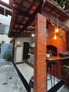 an outdoor kitchen with a brick wall and a bar at Pousada Ilha do sol in Piúma