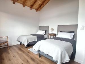 two beds in a room with white walls and wooden floors at Jardin de Estepa Il in Dina Huapi