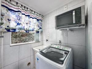 a small kitchen with a washing machine and a tv at Centro, apê 2 Quartos com Ar | Garagem in Brusque +19 photos