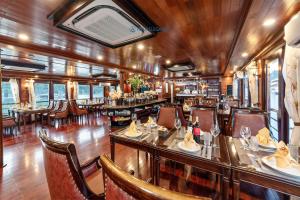 a restaurant with tables and chairs and a bar at Aqua Elegance Cruise - Halong Bay by AHG in Ha Long