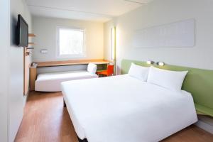 Habitación de hotel con cama blanca y sofá en Ibis Budget Madrid Alcorcón Móstoles en Alcorcón