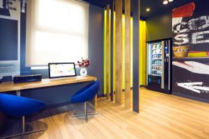 Una oficina con un escritorio con sillas azules y un refrigerador. en Ibis Budget Madrid Alcorcón Móstoles, en Alcorcón