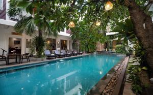 a swimming pool with chairs and trees in a building at Boutique Indochine d'Angkor in Siem Reap