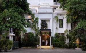 a white building with two people walking into it at Boutique Indochine d'Angkor in Siem Reap
