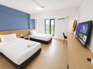 a hotel room with two beds and a flat screen tv at De Botan Bangna in Bangkok