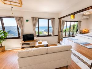 a living room with a couch and large windows at Villa Amoria in Miyazaki
