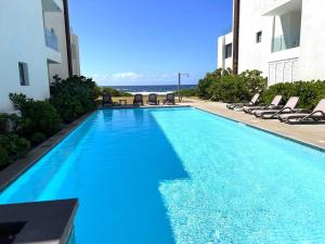 a swimming pool with chairs and the ocean in the background at Eastern Blue Beachfront Apartment in Poste Lafayette