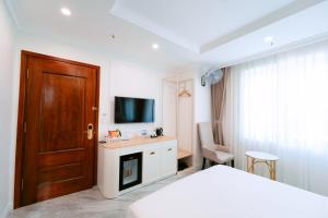 a bedroom with a bed and a tv and a door at Nhật Tân Hotel Triển Lãm VEC - Đông Anh in Dong Anh