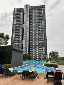 a swimming pool with two tall buildings in the background at Sunset Retreat Sensory Residence in Kampung Dengkil