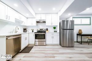 a kitchen with white cabinets and a stainless steel refrigerator at Spacious Bright Suite - Sleeps 4 - King Bed - NFLX in Edmonton