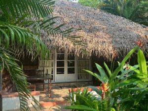 a hut with a thatched roof in a garden at Marari Dreamz Homestay in Mararikulam