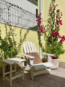 a white chair and a bench next to some flowers at Casa Palma Hostel in Barcelos