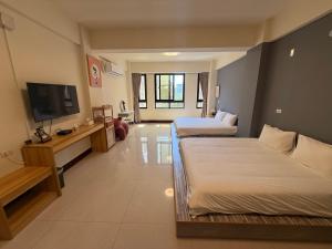a room with two beds and a flat screen tv at 夏米旅宿 in Lukang