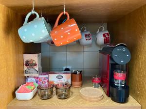 a shelf with cups and utensils and a coffee maker at Casa Palma Hostel in Barcelos +22 photos