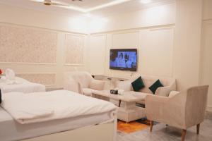 a white room with two beds and a tv at Pc Inn Executive Class Hotel in Sukkur