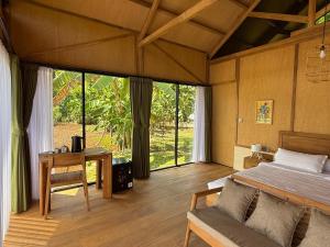 a bedroom with a bed and a desk and windows at Terra Clementia in Watukarung
