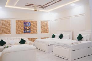 a white room with two beds and couches at Pc Inn Executive Class Hotel in Sukkur