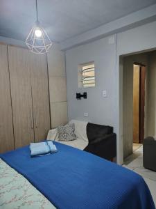 a bedroom with a blue bed and a couch at Casa da Bebel in Uruguaiana