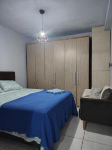 a bedroom with a blue bed and wooden cabinets at Casa da Bebel in Uruguaiana