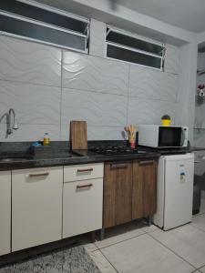 a kitchen with white cabinets and a sink and a microwave at Casa da Bebel in Uruguaiana