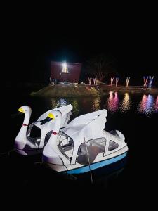 two white boats in the water at night at Nelli Kale Holiday Resort in Huratgamuwa