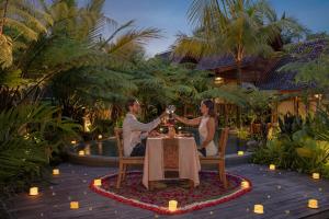 a man and woman sitting at a table with glasses of wine at Edge of Ubud by GenuineHost in Ubud