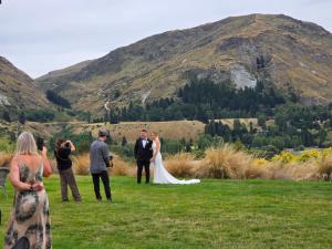 a bride and groom and their wedding party in a field at Tucker Beach Private Exclusive Retreat in Queenstown