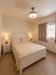 a white bedroom with a large bed and a window at My tropical home in La Laguna