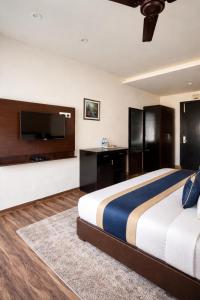 ein Schlafzimmer mit Bett, Schreibtisch und Fernseher in der Unterkunft The Ginger McLeodGanj-By Vaikunth Centrally Heated & Air Cooled # Near Mall Road # Big Parking # Lift #Spacious Rooms # Most Awarded # Property Of The Year # in McLeod Ganj