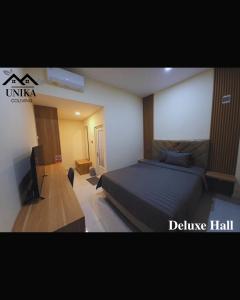 a hotel room with a bed and a television at Unika Coliving Vibes Syariah in Sultan Syarif Kasim II International Airport