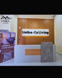 a unitedica colving exhibit with a sign on a wall at Unika Coliving Vibes Syariah in Sultan Syarif Kasim II International Airport