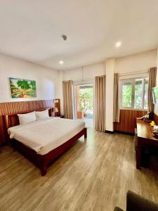 a bedroom with a bed and a desk and windows at Vida Loca Sunset Beach Resort in Phú Quốc