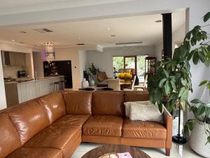 a living room with a brown leather couch and a kitchen at Sunnyhome in Truganina