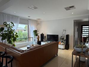 a living room with a brown couch and a large window at Sunnyhome in Truganina