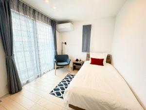 a bedroom with a bed and a chair and a window at Akikawa Koshi 1 プレミアム鉄骨 一棟貸切ヴィラ in Yuge
