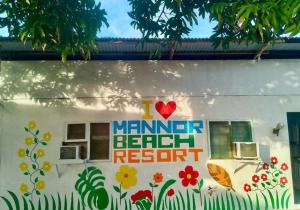 a sign on the side of a building with flowers at Mannor Beach Resort by Hiverooms in Carmen +8 photos