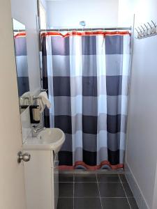 a bathroom with a shower curtain and a sink at The Swiss Motel in Cooma