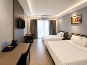 a hotel room with two beds and a desk at B&N HOTEL Hải Tiến in Mỹ Ðuc +7 photos